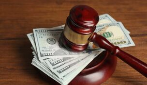 Law gavel with dollars on wooden table background, closeup