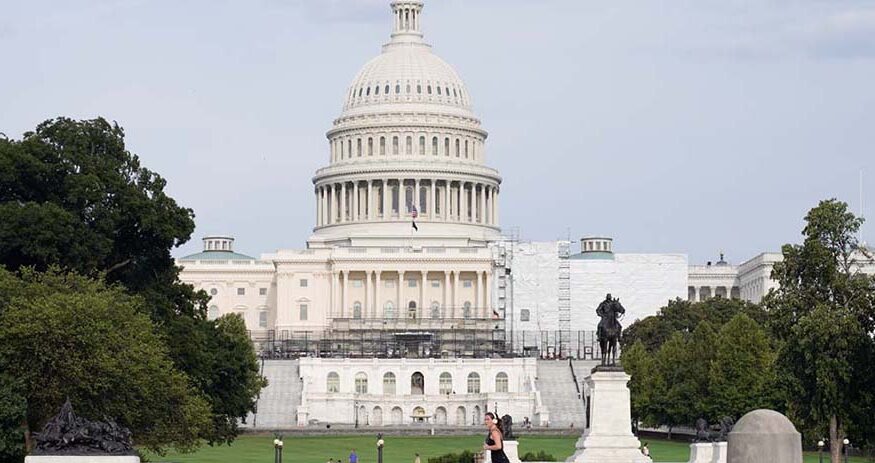 A view of the U.S. Capitol building with a person walking by in the foreground