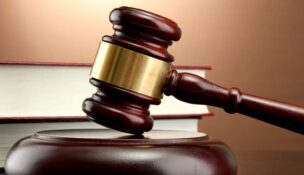 wooden gavel and books on wooden table, on brown background