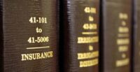 Law books on a shelf with one title in focus that reads "INSURANCE"