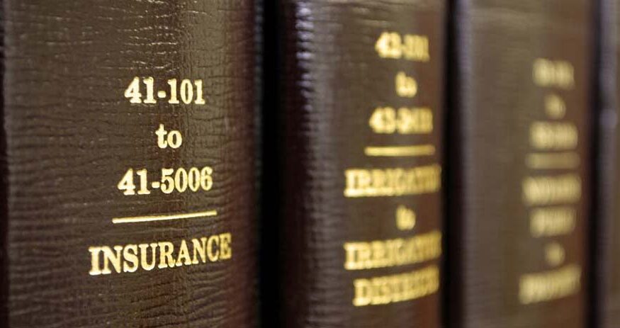 Law books on a shelf with one title in focus that reads "INSURANCE"