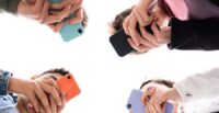 Low angle view of teenager group using phones. Digital addiction and concept.
