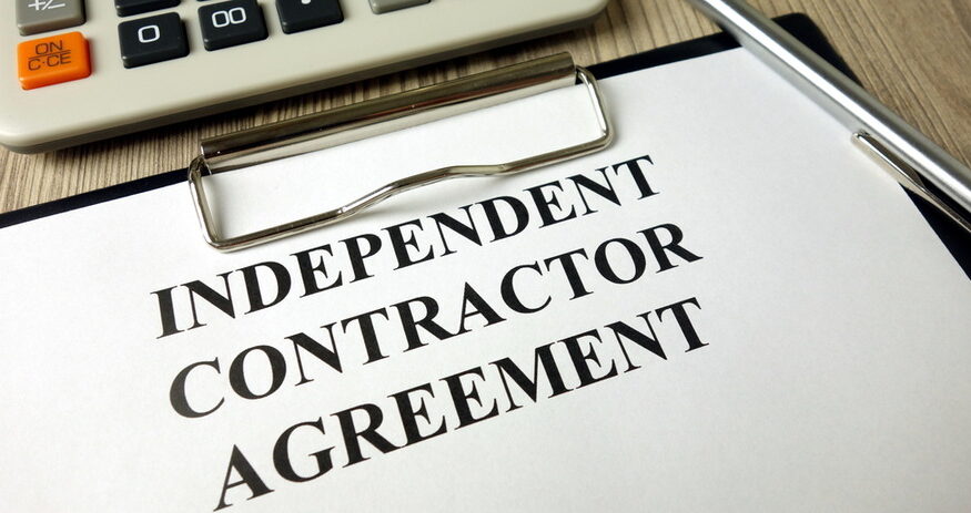 A clipboard with a piece of paper reading "INDEPENDENT CONTRACTOR AGREEMENT"