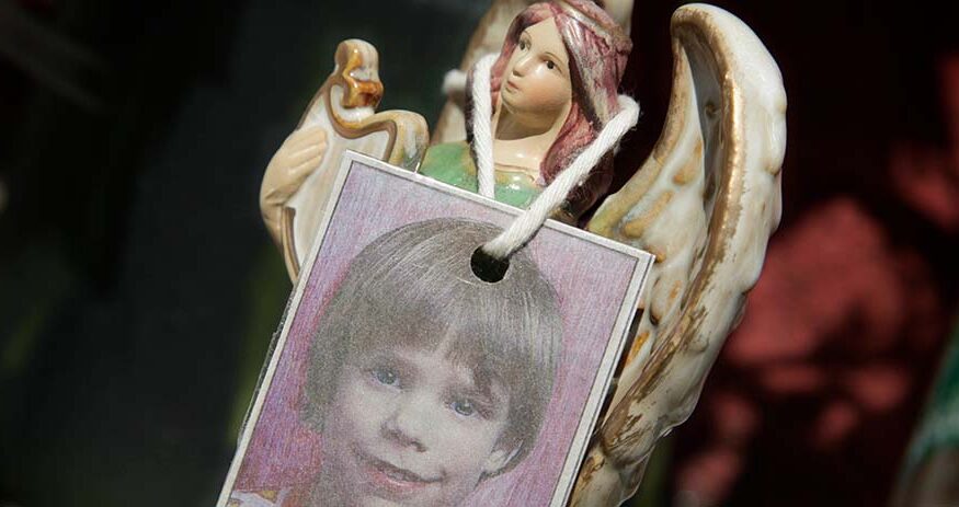 A photograph of Etan Patz hangs on an angel figurine