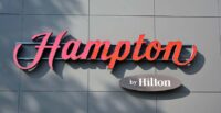 A logo for Hampton by Hilton on the side of a building