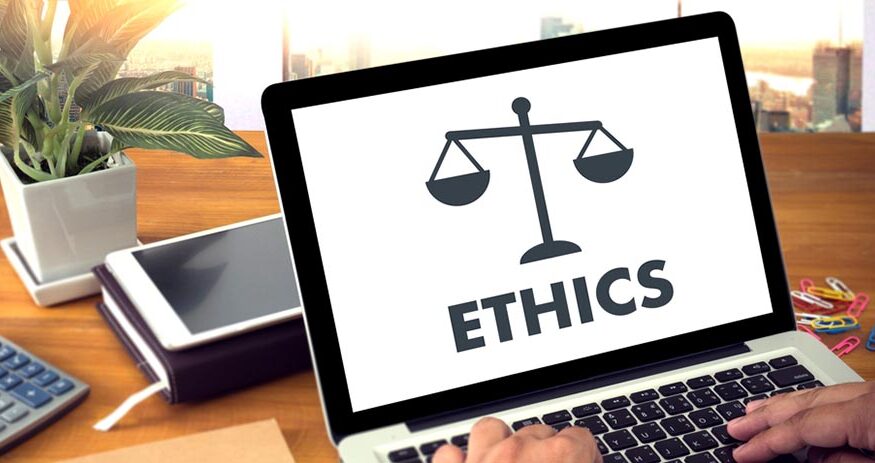An image of a laptop screen with an illustration of the scales of justice on it and the word "ETHICS" underneath