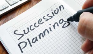 A pen shown finsihing writing "Succession Planning" on graph paper