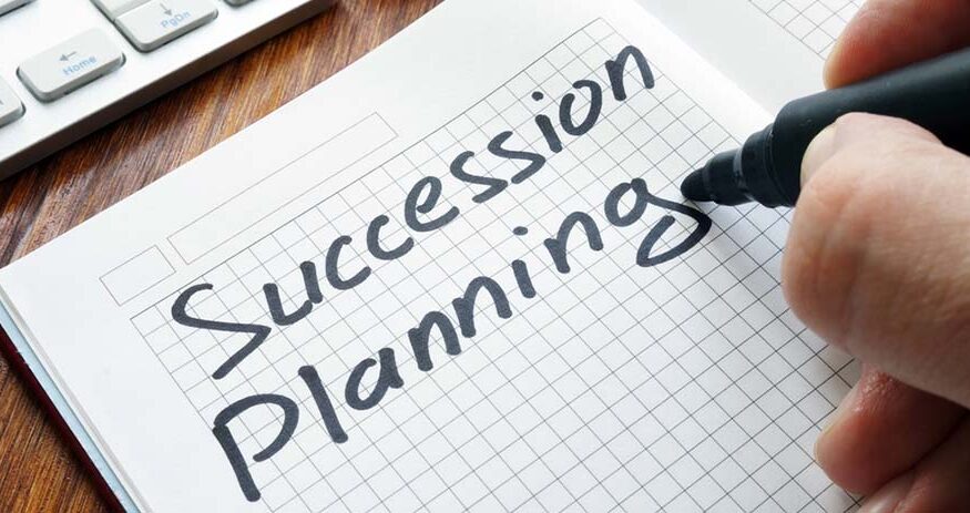 A pen shown finsihing writing "Succession Planning" on graph paper