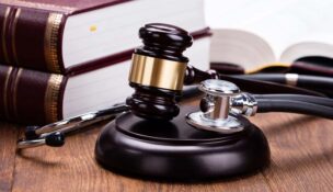 A stethoscope and gavel on a judge's block with two thick textbooks in the background