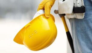 builder with yellow helmet and working gloves on building site