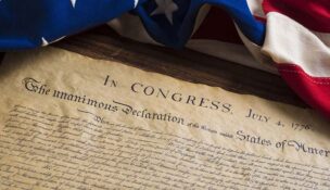The Declaration of Independence with a vintage American flag near it on a table