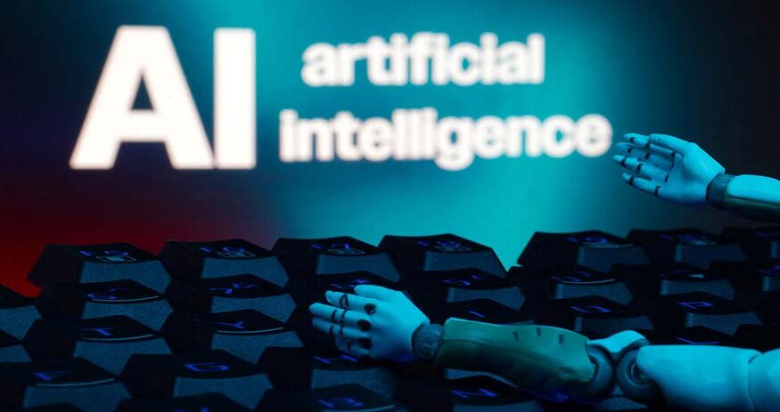 A message reading "AI artificial intelligence", a keyboard, and robot hands are seen in this illustration