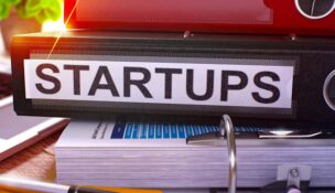 Binders on a desk with one reading "STARTUPS" on the spine facing the viewer